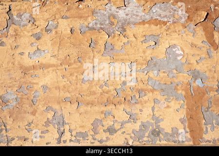 Front view macro shot of an old weathered wall with heavily peeling yellow paint Stock Photo