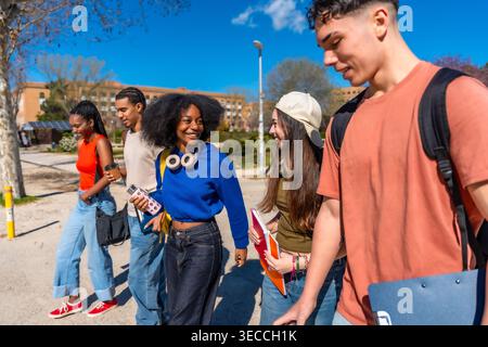 Diverse students walking, talking, and smiling on campus Stock Photo