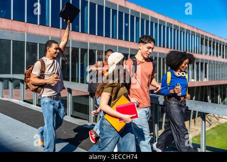 Diverse university students walking together on campus bridge Stock Photo