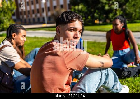 Diverse students relaxing together on university campus grass Stock Photo