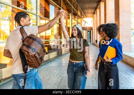 Diverse university students high fiving celebrating success on campus Stock Photo