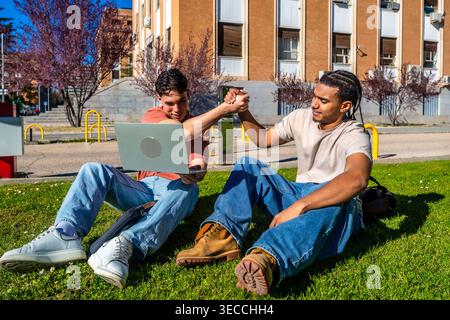 Diverse students collaborating on laptop at university campus Stock Photo