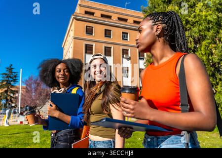 Diverse students walking on university campus discussing together Stock Photo