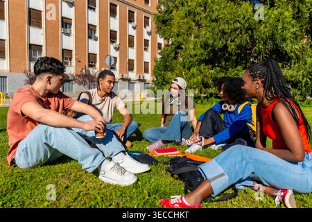Diverse students relaxing, talking on university campus grass Stock Photo