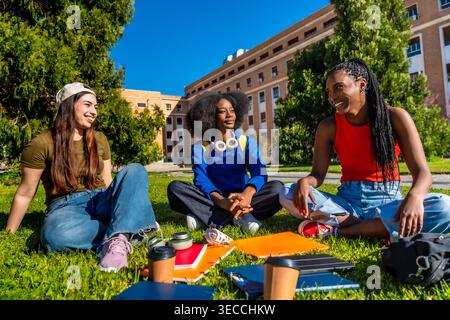 Diverse female students relaxing on university campus grass Stock Photo