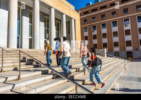 Diverse students walking up stairs on university campus Stock Photo