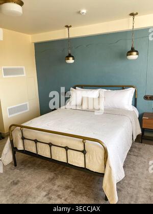 Modern cozy bedroom interior with double bed, soft neutral bedding and blue accent wall, minimal design with warm lighting Stock Photo