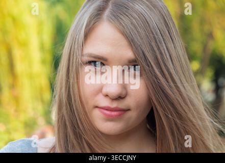 Headshot of a young woman with straight light blonde hair and blue eyes outdoors in natural light Stock Photo