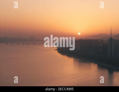 Beautiful sunset over the river with orange glow reflecting on water and bridges Stock Photo