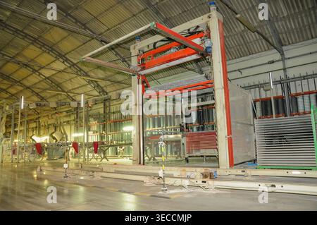 Industrial machine lifts and processes ceramic tiles along a production line inside a factory, highlighting structured workflow and advanced manufactu Stock Photo