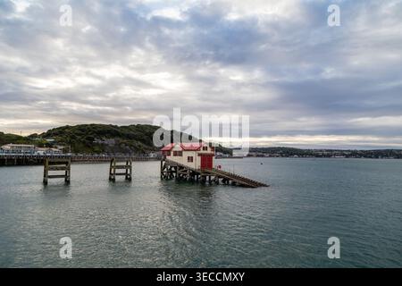 Old Mumbles Lifeboat Station and slipway in Swansea Bay, Wales, featuring iconic red and white Victorian architecture at twilight Stock Photo