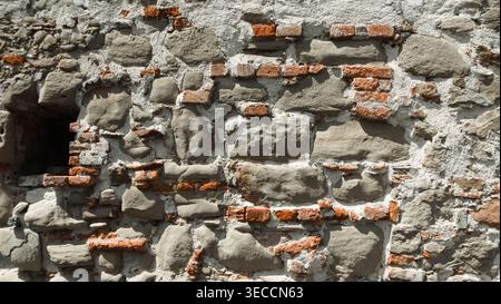 Old stone and brick wall combines weathered gray stones with red bricks bound by mortar.  Stock Photo