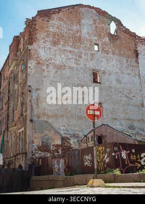 Vyborg, Russia - June 27, 2021: Weathered urban facade of a large old building with exposed bricks and plaster, featuring a street sign Stock Photo