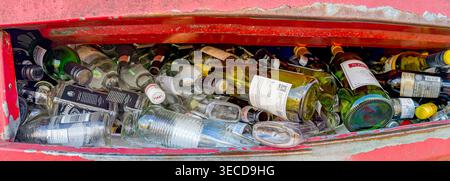 Pontypridd, Rhondda Cynon Taf, Wales, UK - 21 March 2026: Panoramic view of empty wine and spirits bottles in a full recycling container. Stock Photo