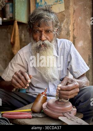 Elderly man with big beard working with tools in a craft environment, India Stock Photo