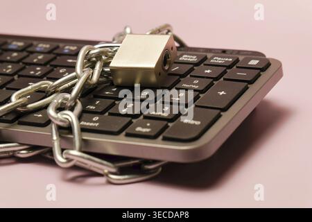 Computer keyboard wrapped in a metal chain and locked with a padlock, representing cybersecurity, data privacy, and internet safety Stock Photo