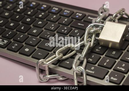 Computer keyboard covered with a metal chain and padlock, symbolizing cybersecurity, data protection, and internet safety Stock Photo