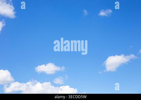 Bright blue sky with scattered white fluffy clouds on a sunny day. Nature, weather, sky background Stock Photo
