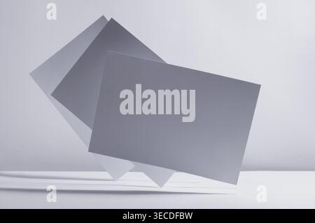 Modern simple geometric white grey abstract background with flying blank rectangle papers in light with shadow. Stock Photo