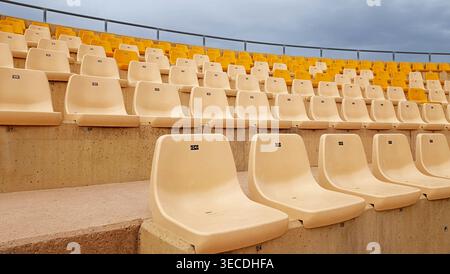 Rows of Empty Yellow and White Seats in Outdoor Stadium Stock Photo