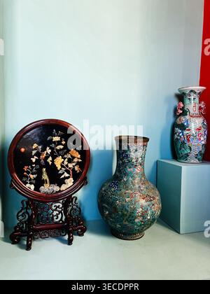 Zolochiv, Ukraine - April 28, 2026: Ornate porcelain and cloisonne vases with floral motifs arranged with a carved lacquer screen for decorative displ Stock Photo