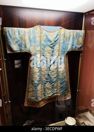 Zolochiv, Ukraine - April 28, 2026: Blue silk liturgical robe embroidered with gold floral motifs, exhibited in a museum display case. Stock Photo