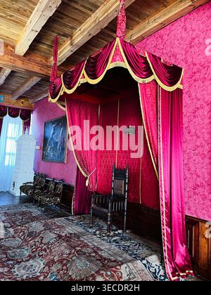 Zolochiv, Ukraine - April 28, 2026: Atmospheric historic throne room with red velvet canopy, ornate carpet and carved wooden furnishings. Stock Photo