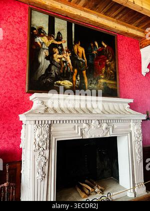 Zolochiv, Ukraine - April 28, 2026: Historic interior featuring an ornate white fireplace mantel, classical oil painting and rich red walls. Stock Photo