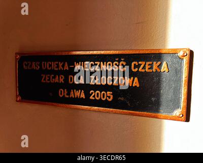 Zolochiv, Ukraine - April 28, 2026: Commemorative metal plaque with Polish text about time and eternity lit by warm side light. Stock Photo
