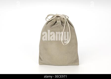Soft taupe beige suede fabric drawstring pouch bag fully closed with a twisted rope cord tie, photographed on a clean isolated white studio background Stock Photo