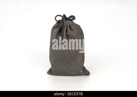 Close-up studio shot of a dark charcoal gray textured fabric drawstring pouch bag secured with a braided nylon cord tied in a neat bow, isolated on a Stock Photo