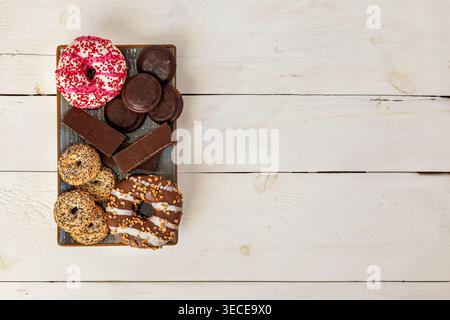 Assorted Donuts And Chocolate Sweets On Tray. Overhead view of assorted donuts, chocolate cookies, and dessert bars on a tray with copy space on Stock Photo