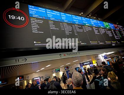 Passengers wait below Euston station departure boards at evening peak, with northbound trains delayed and few services ready to board. Stock Photo