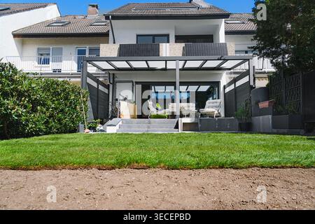 Gardening. Making a lawn from a roll. Green grass texture - well-groomed turf in the garden with a modern house in the background. Stock Photo