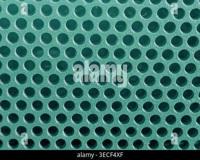 Close-up of shiny perforated metal surface with blurred background and patterned holes Stock Photo