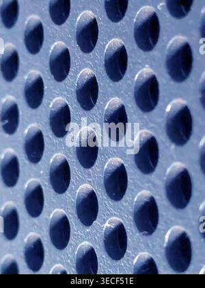 Close-up of shiny perforated metal surface with blurred background and patterned holes Stock Photo