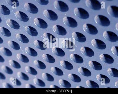 Close-up of shiny perforated metal surface with blurred background and patterned holes Stock Photo