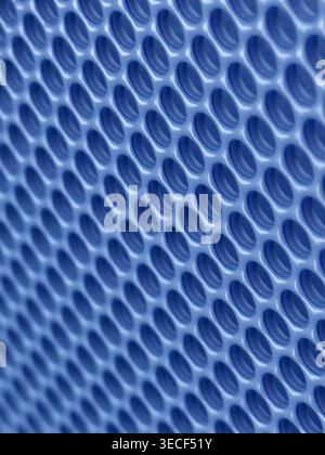 Close-up of shiny perforated metal surface with blurred background and patterned holes Stock Photo