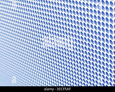 Close-up of shiny perforated metal surface with blurred background and patterned holes Stock Photo