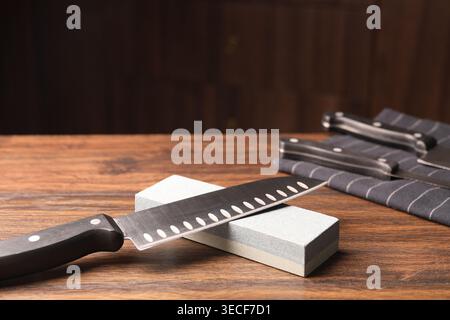 Sharpened knife and whetstone on wooden table. Space for text Stock Photo