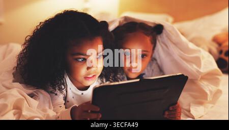 Search, tablet and watching movie with children in bedroom for streaming service, film and night. Series subscription, late entertainment and weekend Stock Photo