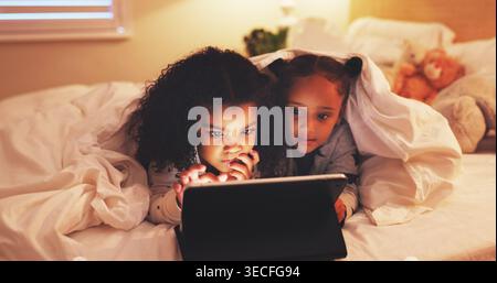 Relax, tablet and watching movie with children in bedroom for streaming service, film and night. Series subscription, late entertainment and weekend Stock Photo