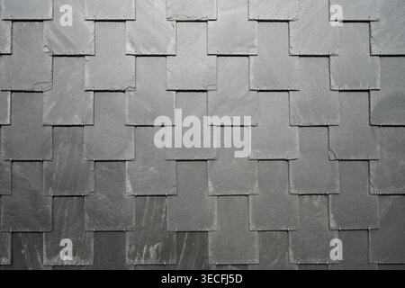 Overlapping dark slate tiles forming textured geometric roofing surface Stock Photo