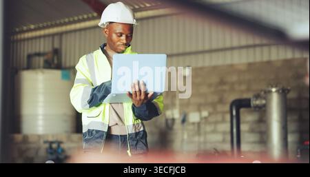 Engineer, laptop and black man in warehouse for hydraulic system, inspection and tank maintenance. Technician, water plant and person on computer for Stock Photo