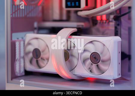 A close-up view of a modern high-performance GPU with three cooling fans and illuminated red lights. Stock Photo