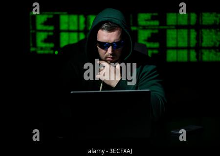 Hacking programmer uses laptop computer. Hacking programmer writes code at night. Hacking programmer monitors server system. Hacking programmer Stock Photo