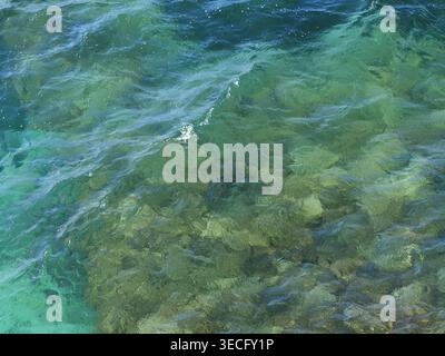 Mediterranean sea water with vibrant turquoise color and gentle waves over rocky seabed. Top view. Copy space. Stock Photo