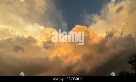 Bright clouds fill the sky during sunset while darker clouds gather in the background This view captures nature and the changing colors of the sky in Stock Photo