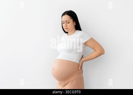Pregnant young woman holding lower back in discomfort, representing pregnancy pain Stock Photo