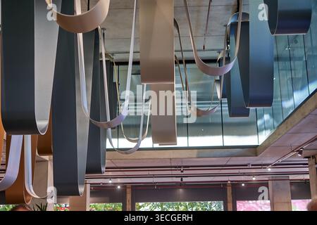 A striking interior view of a modern architectural space in London featuring an elaborate installation of curved, suspended panels hanging from a raw Stock Photo